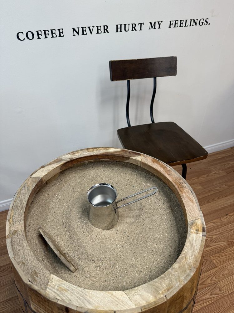 Traditional coffee being brewed in a copper pot on hot sand